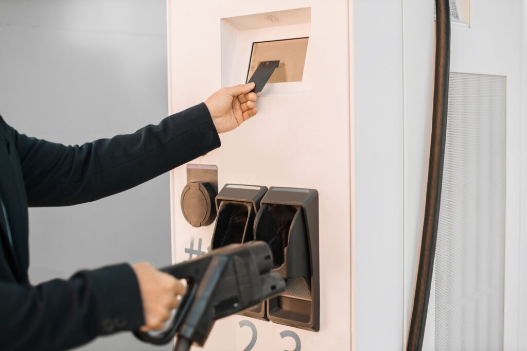 Image showing a user paying for EV charging at a station using a contactless card payment terminal.